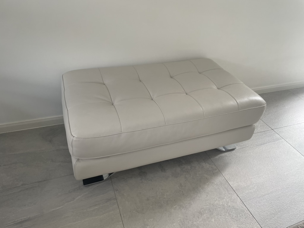Light leather ottoman before the owner-curated restoration sequence