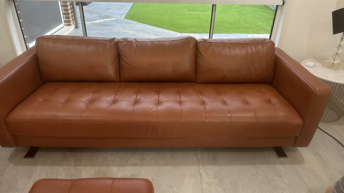 Tan leather three-seat lounge after the owner-curated restoration sequence