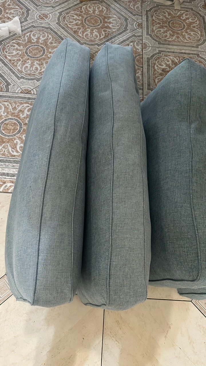 Three blue-grey fabric cushions showing seams and piping