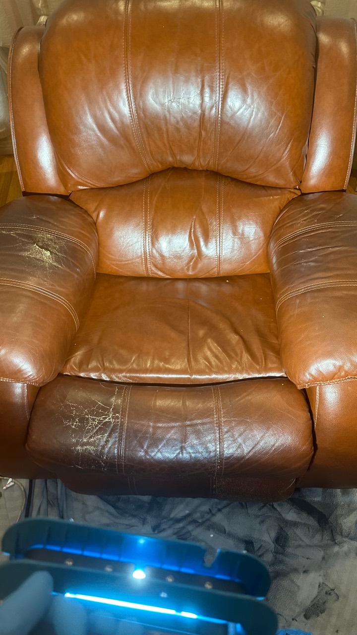 Brown leather recliner before restoration, showing visible wear and colour loss on the arms and footrest